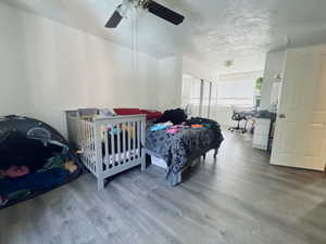 Bedroom featuring a textured ceiling, wood finished floors, and a ceiling fan