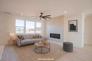 Living area with a glass covered fireplace, recessed lighting, and a ceiling fan