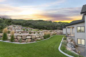 View of grassy yard featuring a balcony