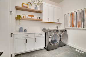 Laundry room with cabinet space, independent washer and dryer, and light tile patterned flooring