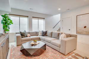 Living area with stairway, recessed lighting, and light colored carpet