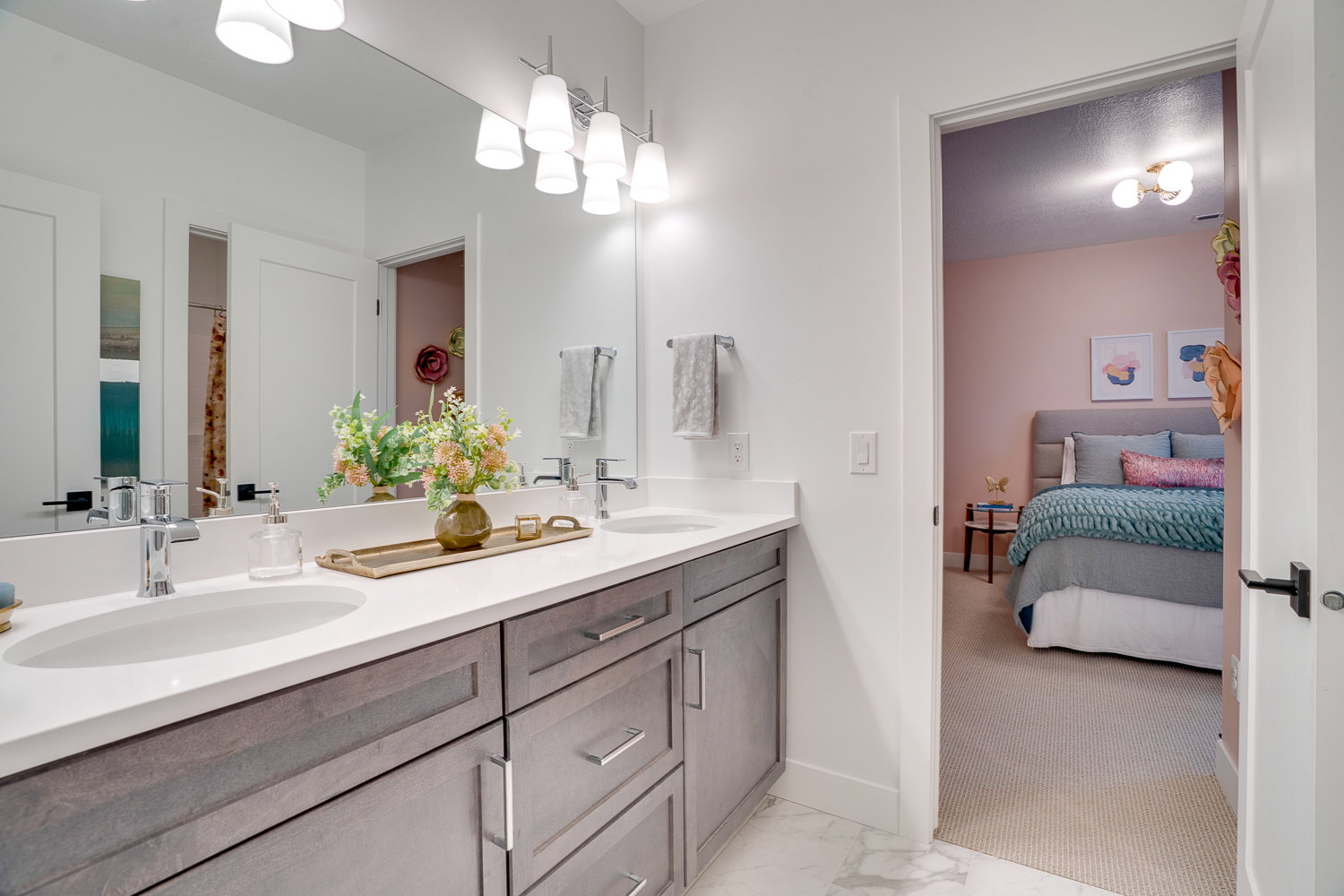 Ensuite bathroom with double vanity, light carpet, and light marble finish floors