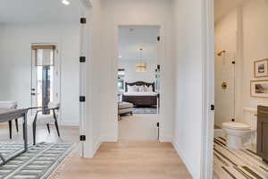 Corridor with light wood finished floors, healthy amount of natural light, and recessed lighting