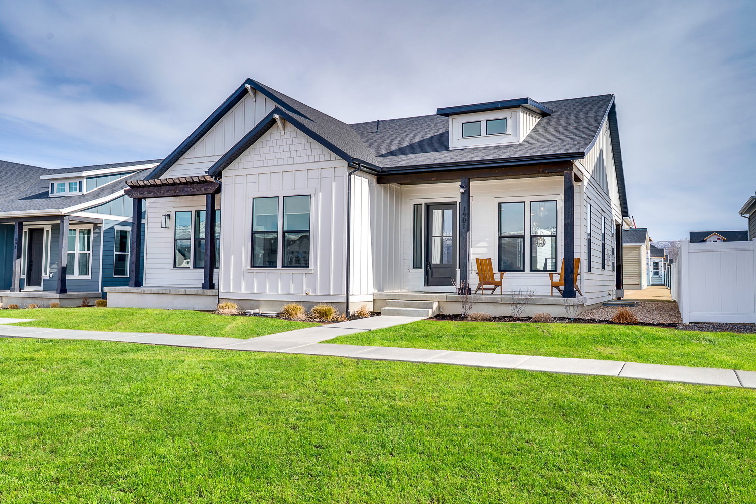 Modern farmhouse style home featuring board and batten siding, a porch, a shingled roof, and a front yard