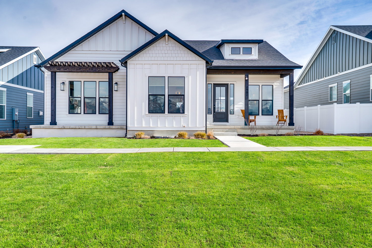 Modern farmhouse with board and batten siding, a front yard, a porch, and roof with shingles