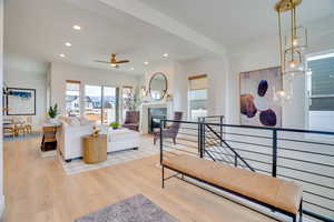 Living room with recessed lighting, a fireplace, light wood-style floors, a chandelier, and a ceiling fan