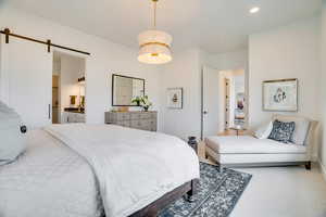 Bedroom featuring a barn door, carpet flooring, connected bathroom, and recessed lighting