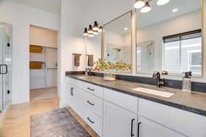 Full bathroom with a marble finish shower, double vanity, and a walk in closet