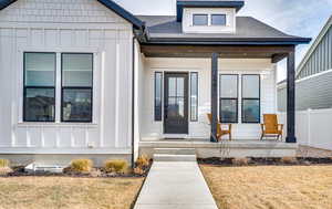 Entrance to property featuring board and batten siding, a shingled roof, and a porch