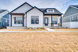Modern farmhouse style home with board and batten siding, a porch, and a shingled roof
