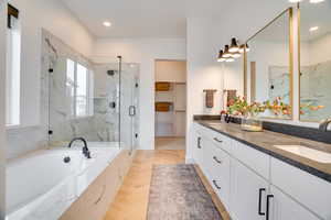 Full bath featuring a marble finish shower, a garden tub, double vanity, a walk in closet, and recessed lighting
