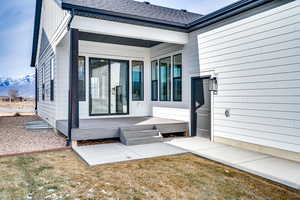 Doorway to property with roof with shingles, a mountain view, and a lawn