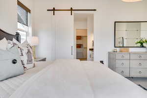 Bedroom featuring a barn door and ensuite bath