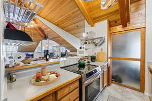 Kitchen featuring wooden ceiling, light countertops, stainless steel range with electric cooktop, white microwave, and brown cabinets