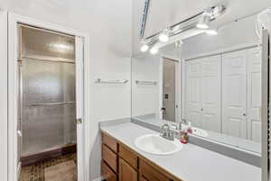 Full bath with vanity, a stall shower, and dark tile patterned flooring