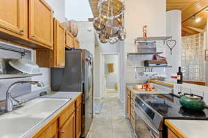 Kitchen with appliances with stainless steel finishes, wood ceiling, light countertops, and brown cabinetry