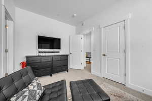 Living area featuring light colored carpet and baseboards