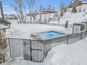 Snowy yard featuring a hot tub and a gate