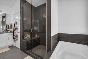 Bathroom featuring a bath, tile patterned flooring, vanity, and a stall shower