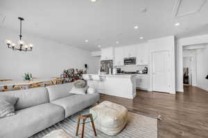 Living area with dark wood-style floors, recessed lighting, and a chandelier