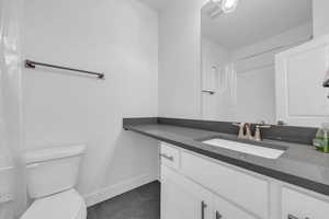 Full bathroom with vanity, curtained shower, and dark tile patterned flooring