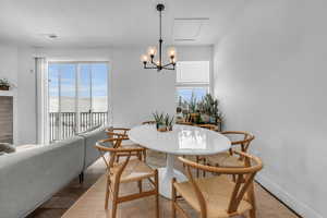 Dining space with a chandelier, healthy amount of natural light, and wood finished floors