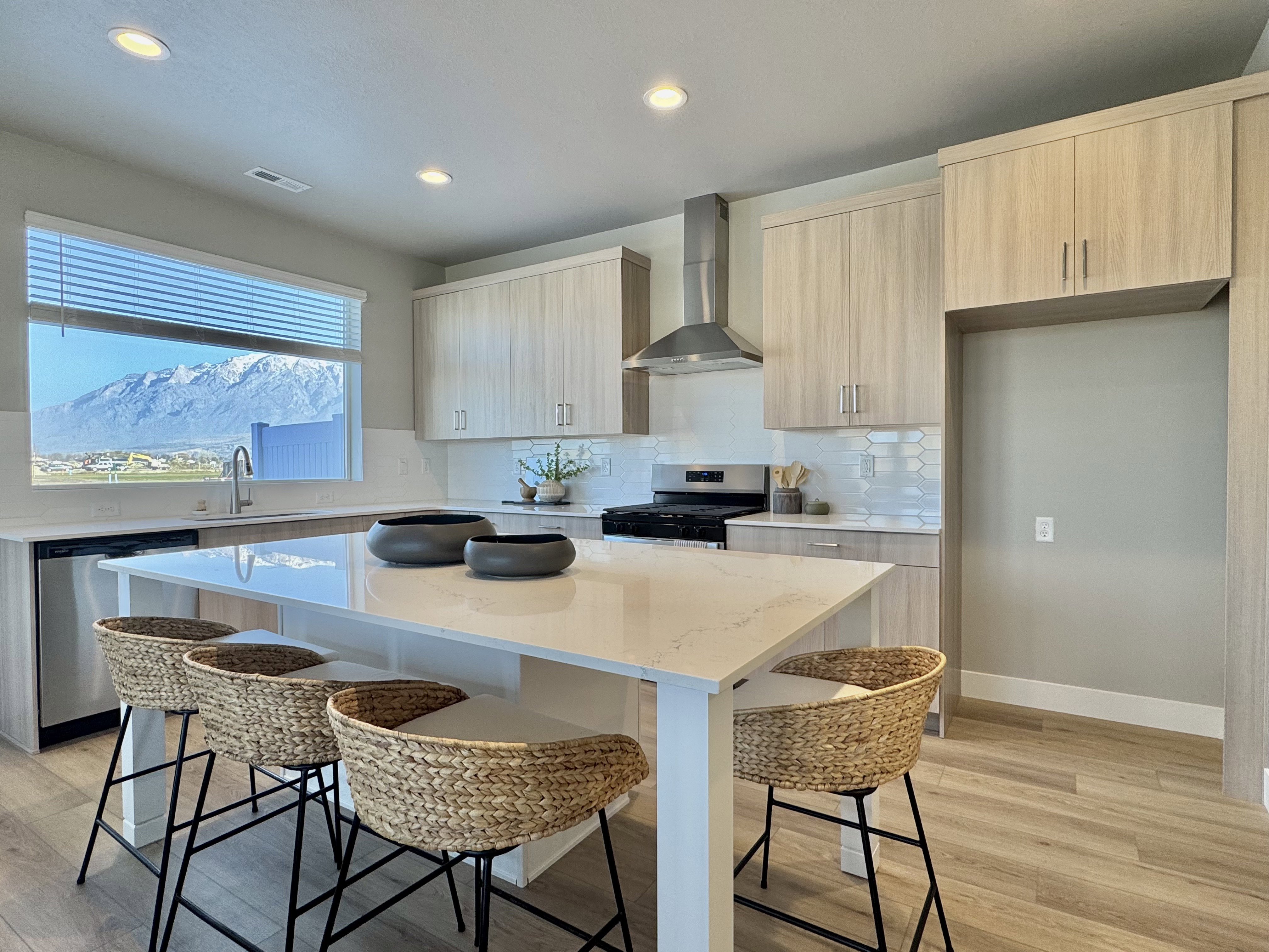 Kitchen with light stone countertops, modern cabinets, wall chimney exhaust hood, a kitchen bar, and stainless steel appliances