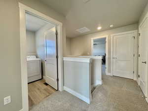 Hallway with washer / clothes dryer, light carpet, recessed lighting, and an upstairs landing