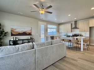 Living area with light wood-type flooring, a ceiling fan, and recessed lighting