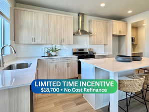Kitchen with light stone counters, light brown cabinets, wall chimney exhaust hood, appliances with stainless steel finishes, and tasteful backsplash