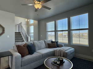 Living area featuring a ceiling fan, stairway, and wood finished floors