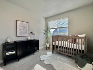 Bedroom with a nursery area and light colored carpet
