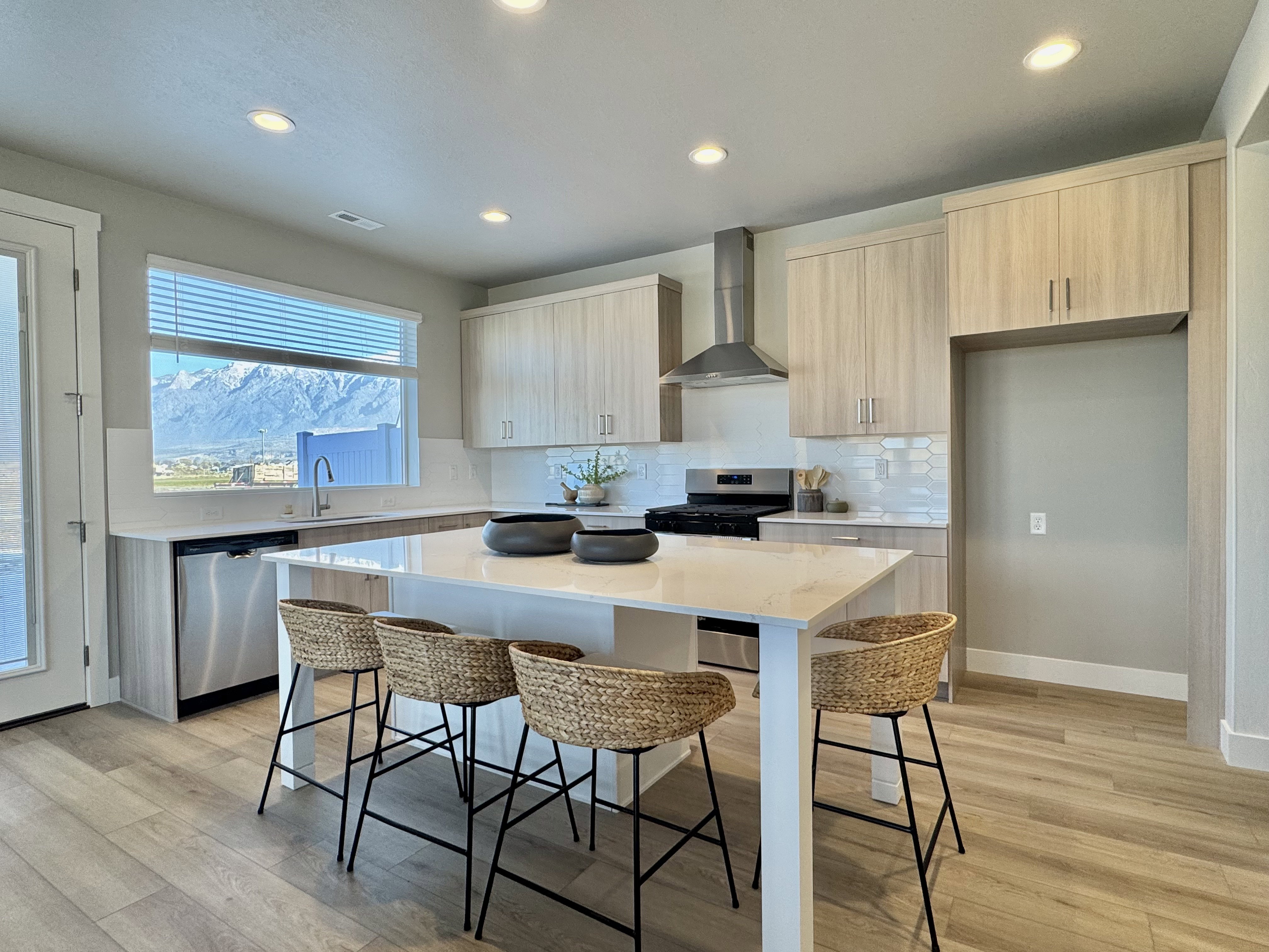 Kitchen featuring modern cabinets, light stone countertops, a kitchen bar, wall chimney exhaust hood, and stainless steel appliances