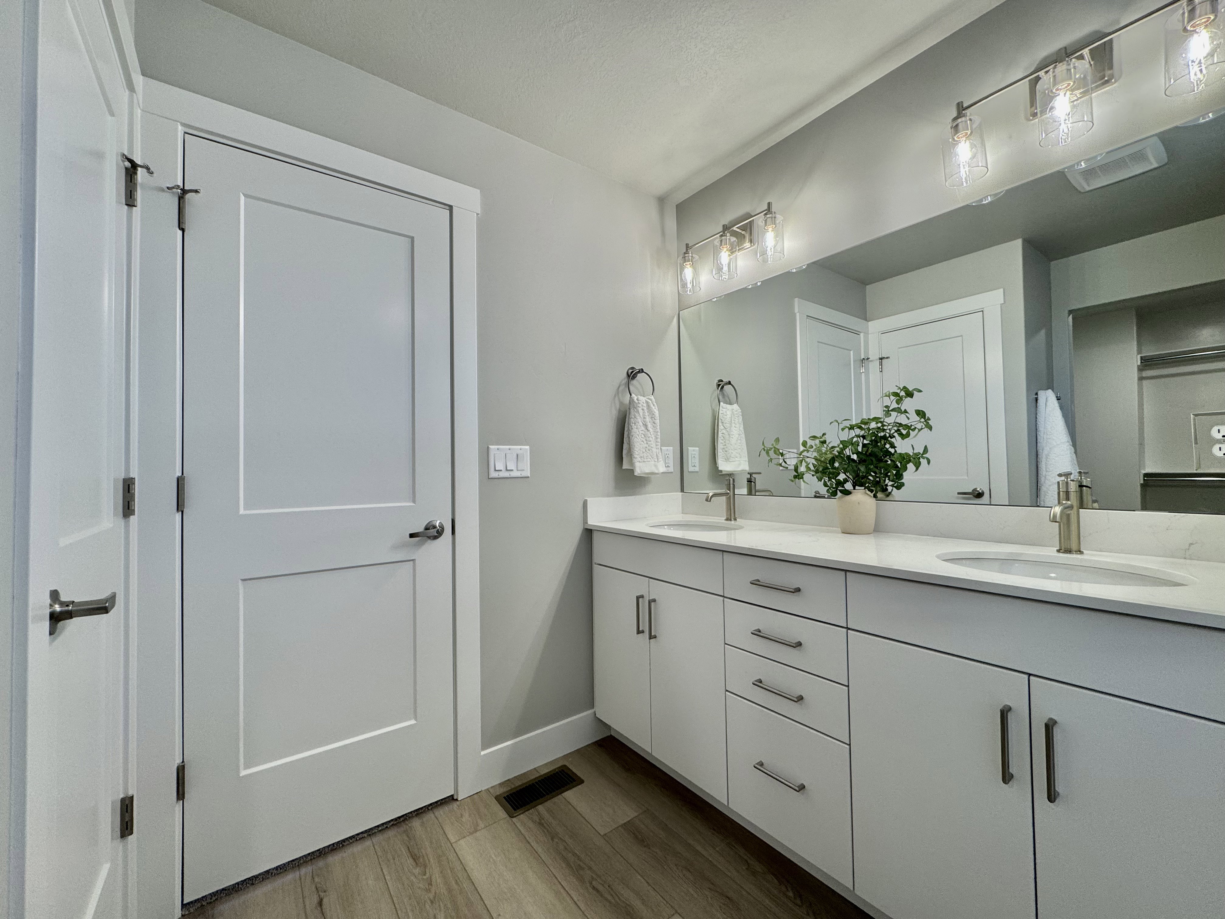 Full bathroom featuring double vanity and dark wood-style floors