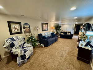 Living area featuring carpet flooring, recessed lighting, and a textured ceiling