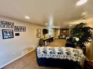 Living room featuring light carpet, a textured ceiling, a fireplace, and recessed lighting