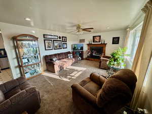 Carpeted living room featuring a ceiling fan, a glass covered fireplace, recessed lighting, and wood walls
