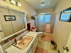 Full bath with vanity, bath / shower combo with glass door, and light tile patterned floors