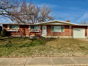 Ranch-style house with a front lawn, brick siding, a garage, a chimney, and crawl space