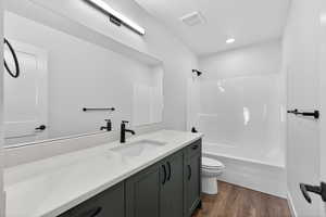 Full bath with vanity, shower / bathtub combination, and dark wood-style flooring