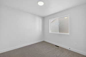 Carpeted spare room featuring baseboards