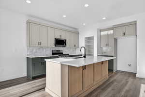 Kitchen featuring gray cabinets, decorative backsplash, stainless steel appliances, and recessed lighting