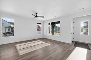 Unfurnished living room featuring healthy amount of natural light, wood finished floors, ceiling fan, and recessed lighting