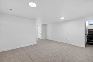 Basement featuring light carpet and stairs