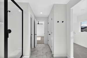 Bathroom featuring light marble finish flooring, a shower stall, and a ceiling fan