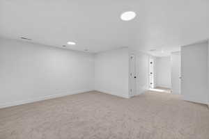 Unfurnished room with light colored carpet and recessed lighting