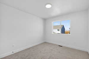 Carpeted spare room with baseboards and a textured ceiling