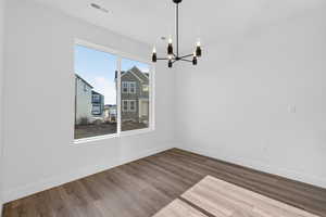 Unfurnished dining area with wood finished floors and a chandelier