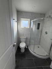 Bathroom featuring a stall shower and dark tile patterned flooring