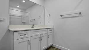 Bathroom featuring vanity, a shower, recessed lighting, and wood finished floors